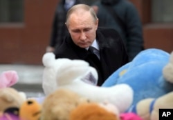 FILE - Russian President Vladimir Putin lays flowers at a memorial made for the victims of a fire in a multi-story shopping center in the Siberian city of Kemerovo, about 3,000 kilometers (1,900 miles) east of Moscow, March 27, 2018.