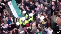 In this image from amateur video made available by the Shaam News Network and shot on Friday, Dec. 30, 2011, Arab League observers are seen at a protest in Idlib, Syria.
