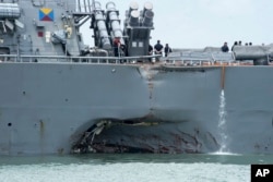 FILE - Damage is visible as the guided-missile destroyer USS John S. McCain steers toward Changi Naval Base in Singapore following a collision this week with the merchant vessel Alnic MC.