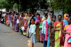 FILE - Women stand in a queue as they wait to receive groceries donated by Institute of the Sisters of Charity to the recent flood affected victims from slum areas in Secunderabad, the twin city of Hyderabad, Nov. 12, 2020.