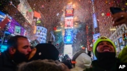 People celebrate as confetti falls down after the countdown to midnight in Times Square, Jan. 1, 2018, in New York. 