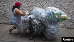 Seorang perempuan berjalan di sepanjang 41st Street dengan tas berisi botol dan kaleng untuk didaur ulang di wilayah Manhattan di New York, 30 September 2015. (REUTERS / Carlo Allegri)