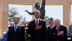 FILE - President Barack Obama and French President Francois Hollande stand with veterans during the playing of Taps, at Normandy American Cemetery at Omaha Beach in Colleville sur Mer, Normandy, France, June 6, 2014.