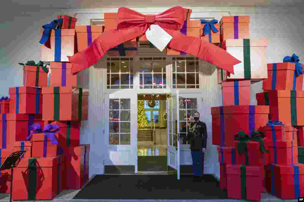 A Marine White House Military social aide holds the door to the East Wing entrance of the White House during a press event for the White House holiday decorations, Monday, Nov. 29, 2021, in Washington. (AP Photo/Evan Vucci)