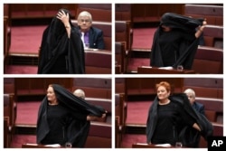 In this combination of photos Sen. Pauline Hanson takes off a burqa she wore into the Senate chamber at Parliament House in Canberra, Australia, Aug. 17, 2017.