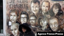 FILE - A woman walks past a mural by French street artist and painter Christian Guemy, known as C215 in Paris, on Jan. 6, 2022, in tribute to staff members of the 'Charlie Hebdo' newspaper who were killed by jihadist gunmen in Jan. 2015.