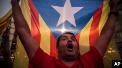 A pro-independence supporter holds up a "estelada" or pro independence flag as crowds gather in the square outside the Palau Generalitat in Barcelona, Spain, on Friday, Oct. 27, 2017. (AP Photo/Santi Palacios)