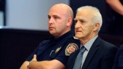 Dragan Vasiljkovic, right, a former Serb military commander sits between guards in a courtroom at the beginning of his trial in Split, Croatia, Sept. 20, 2016.