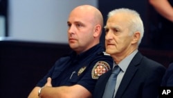 FILE - Dragan Vasiljkovic, right, a former Serb military commander sits between guards in a courtroom at the beginning of his trial in Split, Croatia, Sept. 20, 2016. Vasiljkovic is accused of overseeing the torture and murder of civilians and prisoners in Croatia in the early 1990s.