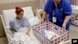 Keyshla Rivera smiles at her newborn son Jesus as registered nurse Christine Weick demonstrates a baby box before her discharge from Temple University Hospital in Philadelphia.