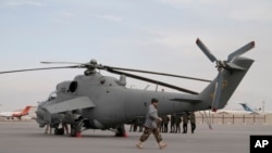 An Afghan soldier walks past Indian-donated helicopters to Afghanistan at the Kabul airport in Kabul, Dec. 25, 2015. India donated four Mi-25 attack helicopters to the Afghanistan Air Force.