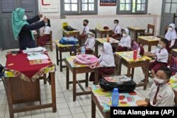 Students wearing face masks to help prevent the spread of COVID-19 attend a class during the first day of school reopening at an elementary school in Jakarta, Indonesia, Monday, Aug. 30, 2021(AP Photo/Dita Alangkara)