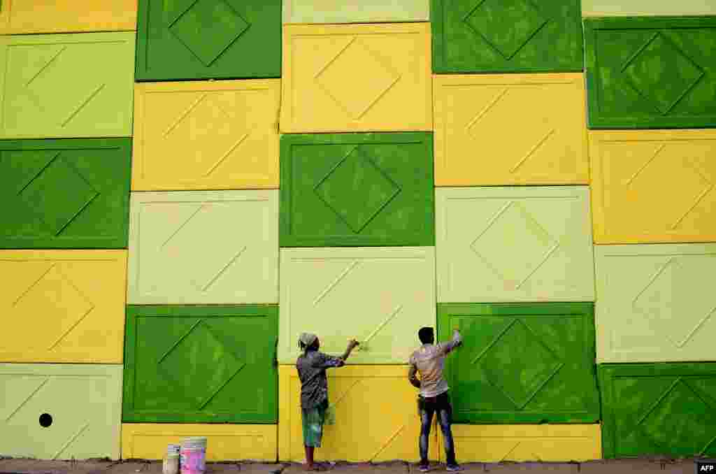 Indian workers paint the wall of a flyover on a road in Jalandhar.