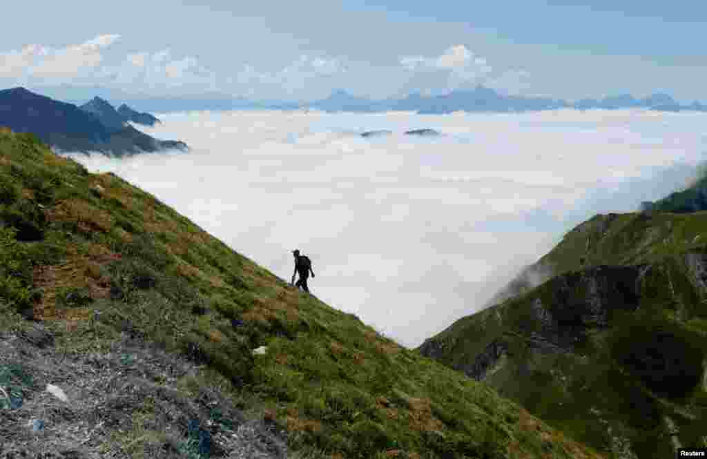 Seorang pendaki berjalan ke puncak Moleson sementara awan tampak di bawahnya di kota Gruyeres, Swiss. (Foto: Reuters)