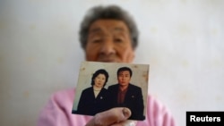 FILE - Park Gyu-soon, whose two sons were abducted in 1972 by North Koreans, poses for photographs with a picture of her second son (R) at her house in Nongso village in Geoje, October 29, 2013.
