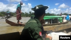 A Myanmar soldier patrols in a boat at the Mayu river while boats deliver food to isolated communities near Buthidaung in the north of Rakhine state, Sept. 13, 2017. 