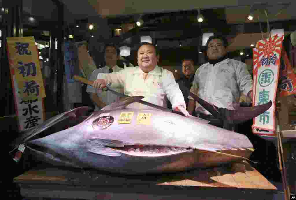 Kiyoshi Kimura, center, president of Kiyomura Co., poses with the bluefin tuna he made a winning bid at the annual New Year auction, at his Sushi Zanmai restaurant near Tsukiji fish market in Tokyo, Japan.