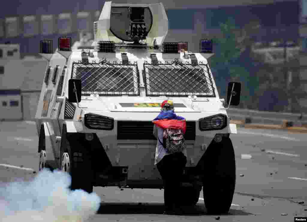 An opposition demonstrator blocks the way of an armored vehicle as riot police clash with demonstrators during the so-called "mother of all marches" against Venezuela's President Nicolas Maduro, in Caracas, April 19, 2017.