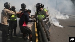 FILE - Venezuelan state security forces detain a protester amid tear gas during a demonstration by opponents of President Nicolas Maduro blocking a major highway in Caracas, Venezuela, May 20, 2017.