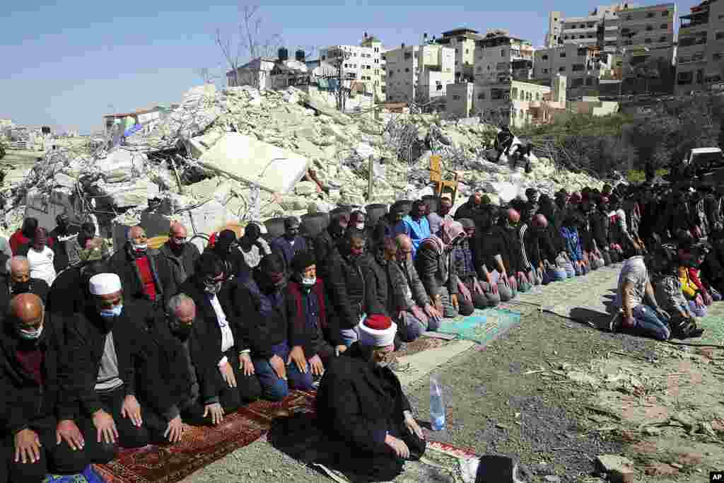 Muslim Palestina melakukan ibadah sholat Jumat di depan puing-puing rumah warga Palestina yang dihancurkan pasukan Israel, selama aksi protes di Yerusalem, Jumat (26/2) (Foto: Mahmoud Illean / AP).