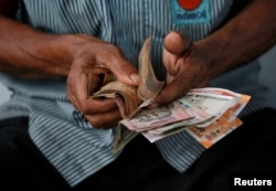 An attendant at a fuel station arranges Indian rupee notes in Kolkata, India, Aug. 16, 2018.