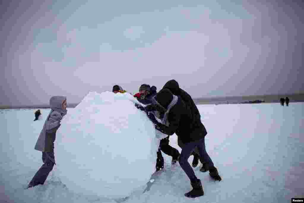 People make a giant snow ball during a winter storm at Brighton Beach, New York, Feb. 1, 2021.