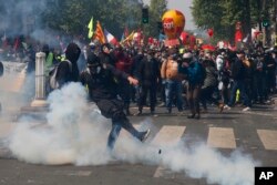An activist kicks away a tear gas canister during a May Day demonstration in Paris, Wednesday, May 1, 2019.