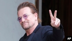 FILE - U2 singer Bono makes a peace sign as he arrives for a meeting at the Elysee Palace, in Paris, France, July 24, 2017.