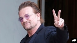 FILE - U2 singer Bono makes a peace sign as he arrives for a meeting at the Elysee Palace, in Paris, France, July 24, 2017.