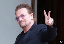 FILE - U2 singer Bono makes a peace sign as he arrives for a meeting at the Elysee Palace, in Paris, France, July 24, 2017.