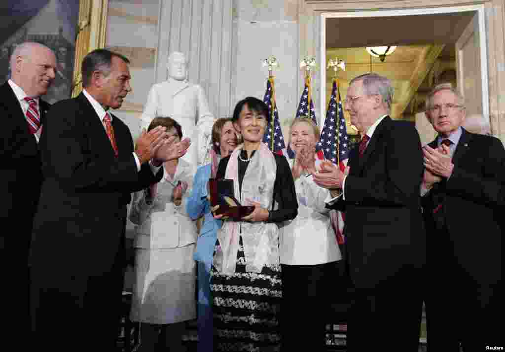 Burma&#39;s democracy leader Aung San Suu Kyi holds her Congressional Gold Medal after it was presented to her by House Speaker John Boehner (R-OH) (2nd L), at the U.S. Capitol in Washington, September 19, 2012. 