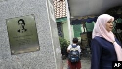 A school official (R) leaves as students look at the newly set-up bronze statue depicting President Obama as a boy at the Menteng One primary school of Jakarta, 22 Feb 2010