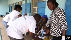 FILE - Health workers take a blood sample from a child in Gusau, northern Nigeria.
