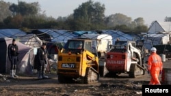 La police anti-émeute sécurise les travailleurs et les grosses machines qui démolissent les habitations de fortune des migrants à Calais, France, 27 octobre 2016. 