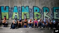 Anti-government demonstrators sit under a bridge that has graffiti written in Spanish that reads "Hunger," during a protest in Caracas, Venezuela, July 1, 2017.