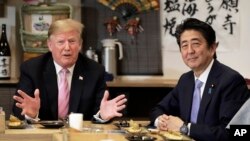 Presiden AS Donald Trump (kiri) berbicara dengan PM Jepang Shinzo Abe di restoran Inakaya, Roppongi, Tokyo Minggu (26/5). 