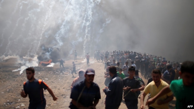 Des manifestants palestiniens lors d'une manifestation contre l'ambassade américaine à Jérusalem, à la frontière entre Israël et Gaza à l'est de la ville de Gaza, le 14 mai 2018.