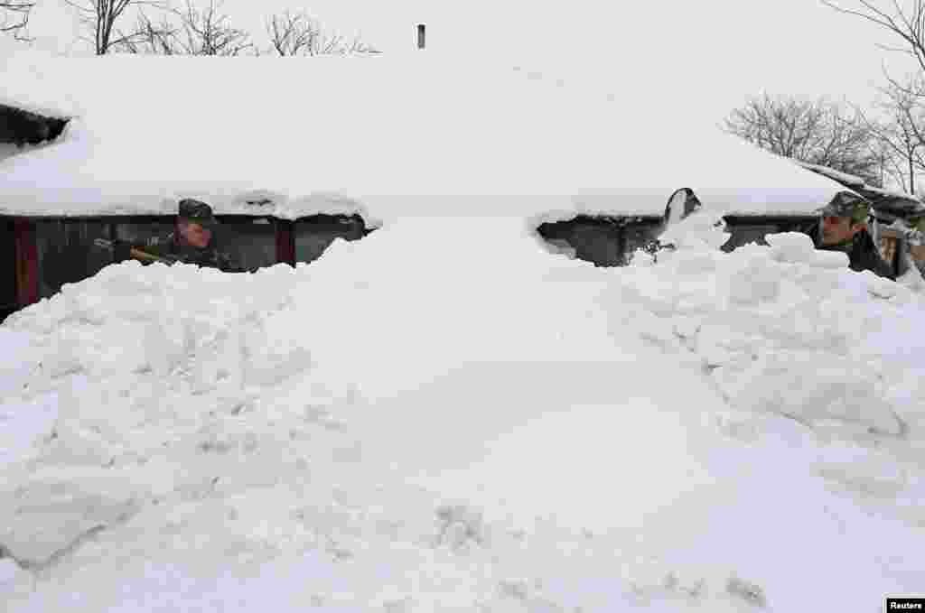 Soldiers shovel the snow in front of a house after heavy snowfall in Vadu Pasii village, 120 km (75 miles) northeast of Bucharest. A powerful snowstorm hit southern Romania over the weekend causing traffic and heating problems in the Balkan country.