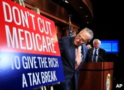 Senate Minority Leader Chuck Schumer of New York, followed by Sen. Bernie Sanders, I-Vt., look at a poster at the start of a news conference on Capitol Hill in Washington, Oct. 4, 2017, urging Republicans to abandon cuts to Medicare and Medicaid.
