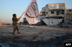 A Turkish-backed Syrian rebel holds the flag of his division in the northwestern border town of al-Bab on Feb. 23, 2017, after they fully captured the town from the Islamic State (IS) group.