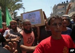 Dolientes palestinos entonan consignas islámicas mientras portan el ataúd de la madre embarazada Enas Khamash de 23 años y su hija Bayan, cuyo retrato está sobre el ataúd, durante su funeral en Deir el Balah, en el centro de la Franja de Gaza, el jueves 9 de agosto de 2018.