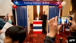 People try out a mock polling station at a hotel during a US presidential election results event organized by the US embassy in Beijing, November 7, 2012.