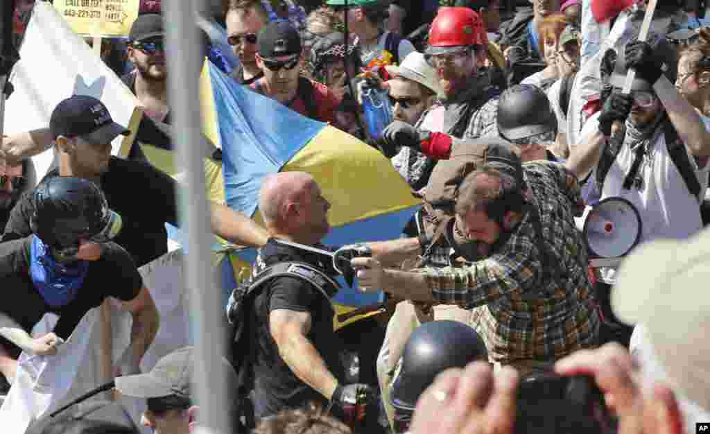 White nationalist demonstrators clash with counter demonstrators at the entrance to Lee Park in Charlottesville, Va., Aug. 12, 2017. Gov. Terry McAuliffe declared a state of emergency and police dressed in riot gear ordered people to disperse after chaoti