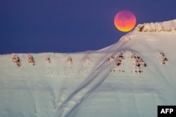 A super blue blood moon behind a mountain is seen from Longyearbyen, Svalbard, Norway, Jan. 31, 2018.