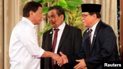 Philippine President Rodrigo Duterte, left, greets Moro Islamic Liberation Front (MILF) chairperson Al Haj Murad Ebrahim, right, while Mohagher Iqbal, MILF peace panel chairman, looks on during a handover of a draft law of the Bangsamoro Basic Law (BBL) in a ceremony at the Malacanang presidential palace in metro Manila, Philippines, July 17, 2017. 
