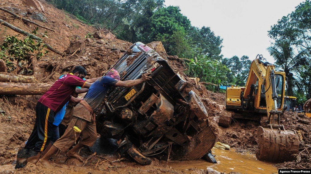 Para petugas SAR mencoba mendorong truk yang terguling di lumpur dan puing-puing di lokasi tanah longsor akibat hujan deras di Kokkayar, negara bagian Kerala, India, Minggu, 17 Oktober 2021.