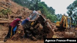 Para petugas SAR mencoba mendorong truk yang terguling di lumpur dan puing-puing di lokasi tanah longsor akibat hujan deras di Kokkayar, negara bagian Kerala, India, Minggu, 17 Oktober 2021.
