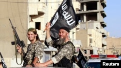 Fighters with the militant group Islamic State in Iraq and the Levant (ISIL) wave flags in northern Syria in June. 