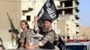 Fighters with the militant group Islamic State wave flags as they hold a military parade along the streets of Raqqa in northern Syria, June 30, 2014. 