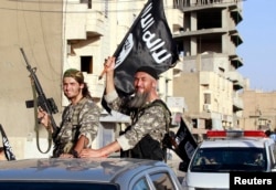 FILE - Fighters with the militant group Islamic State in Iraq and the Levant (ISIL, also called ISIS by some) wave flags as they take part in a military parade along the streets of Raqqa province, northern Syria, June 30, 2014.